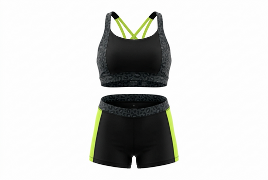 A two-piece athletic set featuring a black sports bra with neon yellow-green straps and patterned gray sides, paired with matching black shorts that have neon yellow-green side panels and a patterned gray waistband.