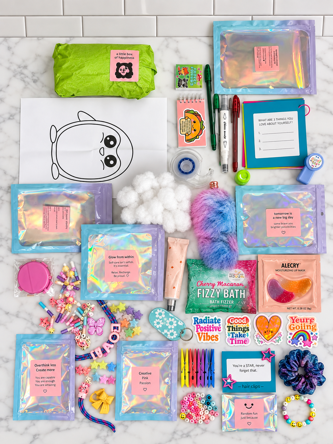 A flat-lay arrangement of colorful self-care and bath products on a white marble surface with subway tile background. Items include iridescent pouches, a lime green bag, bath salts, a fluffy bath bomb, cotton balls, pens, a notepad, stickers, and small accessories.